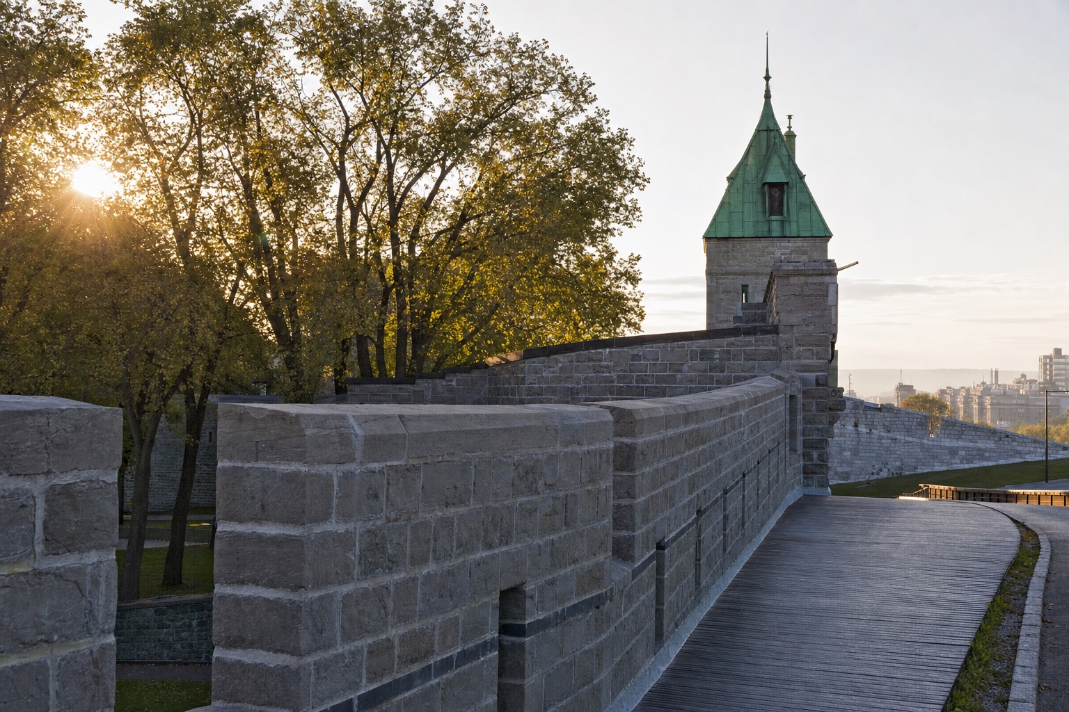 Stone ramparts of Old Quebec's fortifications curving past a gate tower in early morning light