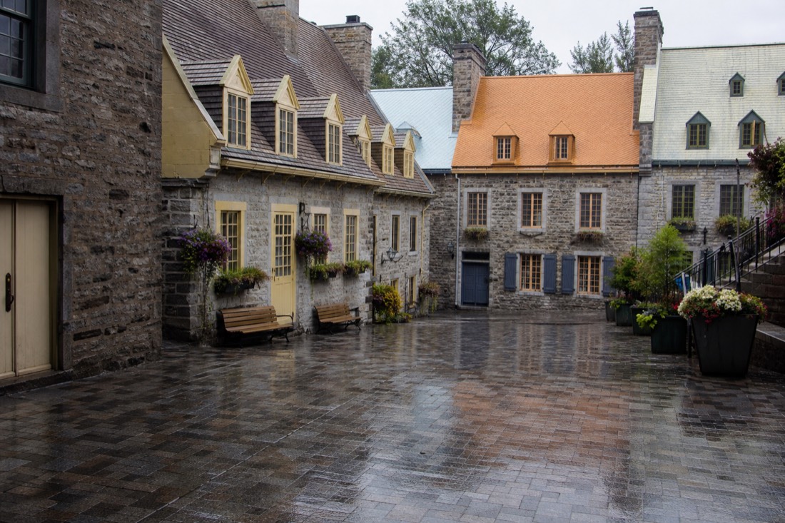 Rainy day on Place Royale in Quebec City with families sheltering under shop awnings