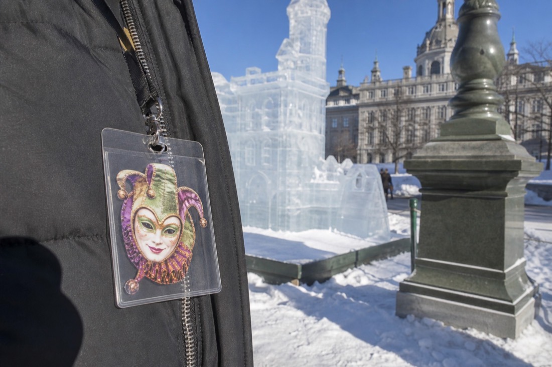 Carnival Effigy pass worn on a winter coat zipper in front of an ice sculpture in Quebec City