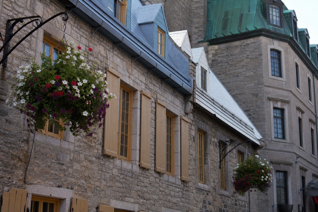 Stone facades and hanging flower baskets on Place Royale in Old Quebec's Lower Town