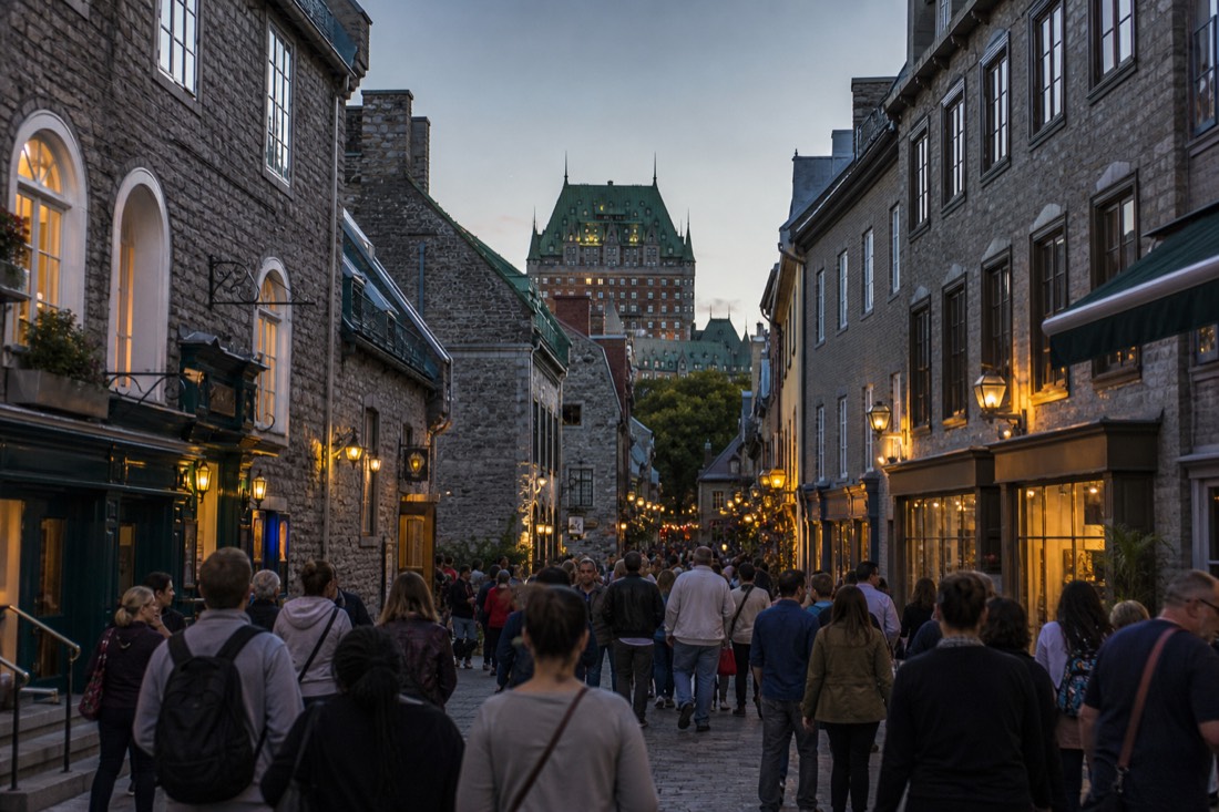 Evening crowd strolling free public streets of Old Quebec under glowing shop windows