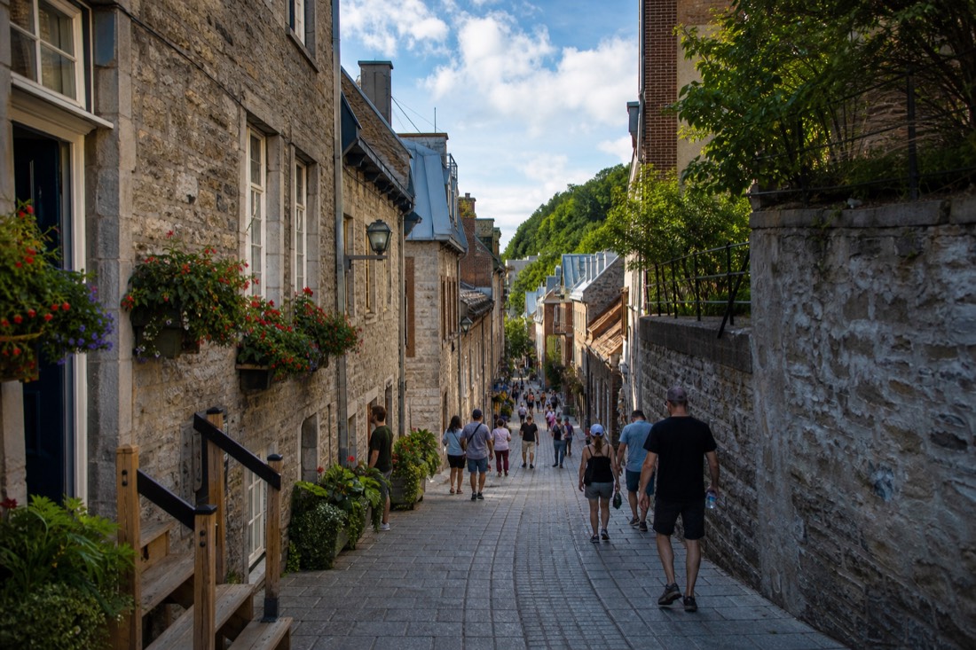 Visitors and locals mingling on a cobbled street in Petit Champlain, Quebec City on a summer afternoon
