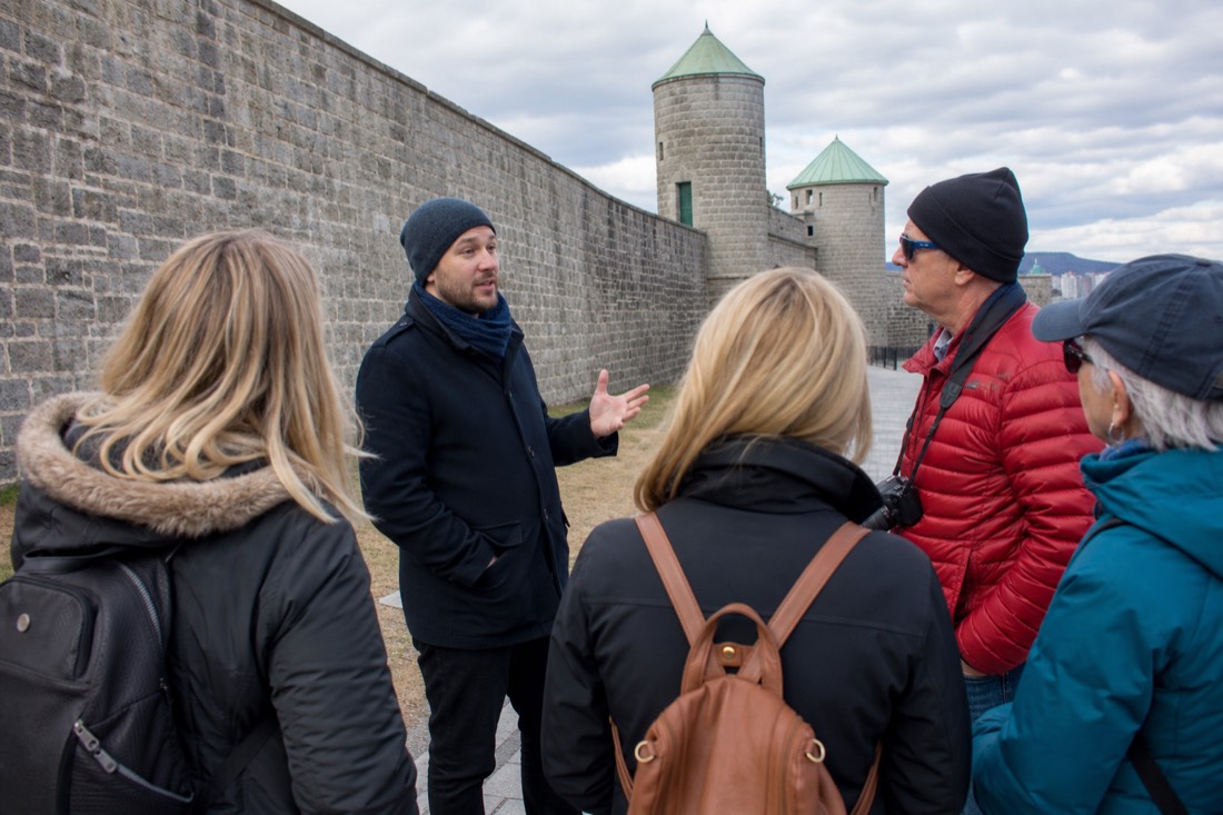 Bilingual tour guide talking with a small group of American tourists beside the fortification walls of Old Quebec