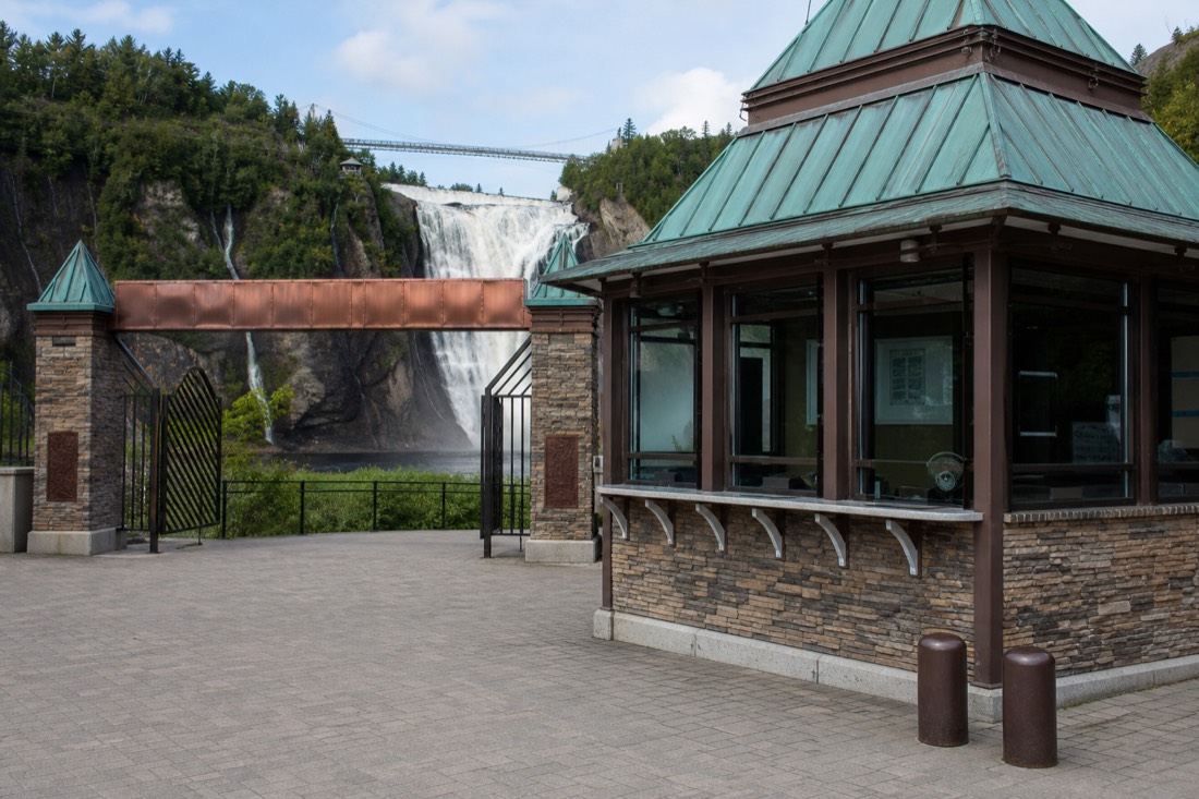 Ticket booth and entrance signage at Parc de la Chute-Montmorency with the falls visible behind