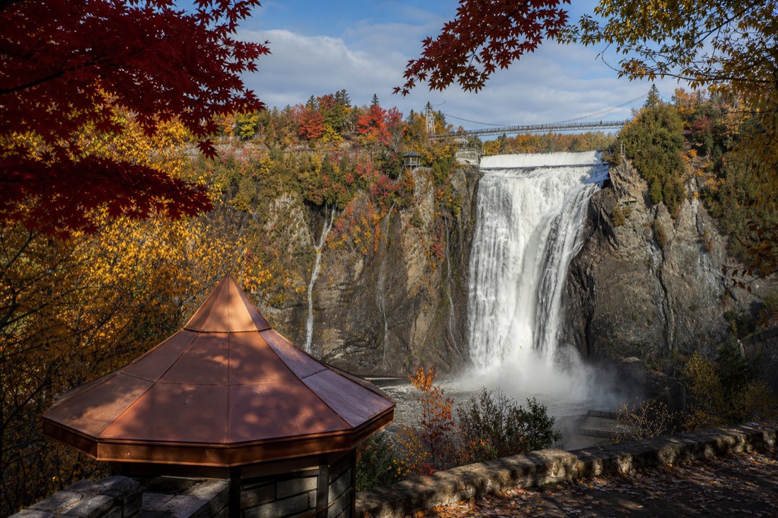 Montmorency Falls in autumn with red and gold foliage framing the boardwalk viewpoints