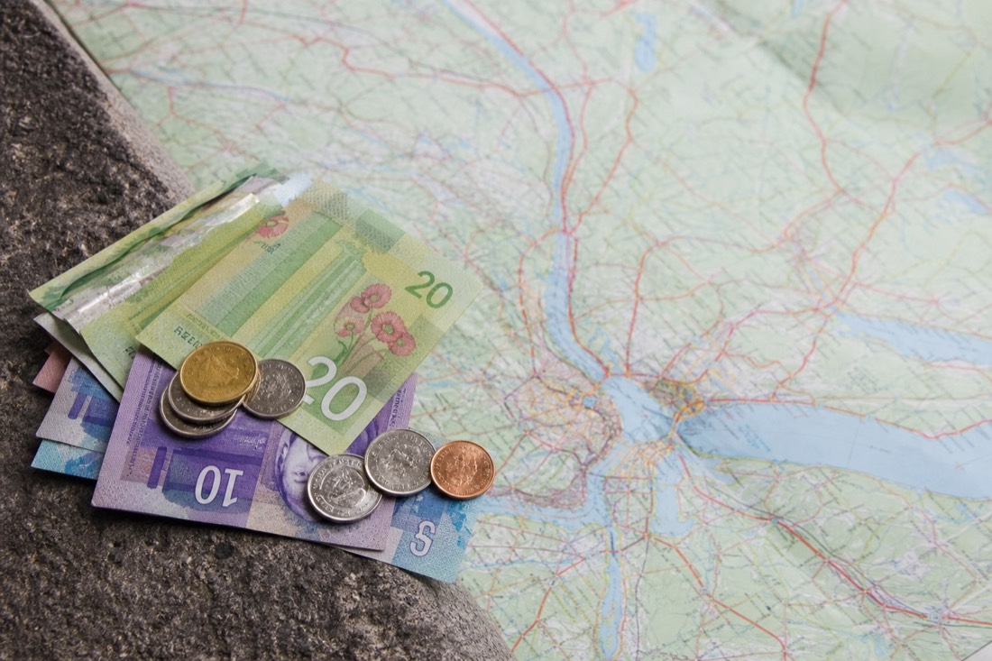 Canadian dollar bills and coins beside a road map of the Quebec City region