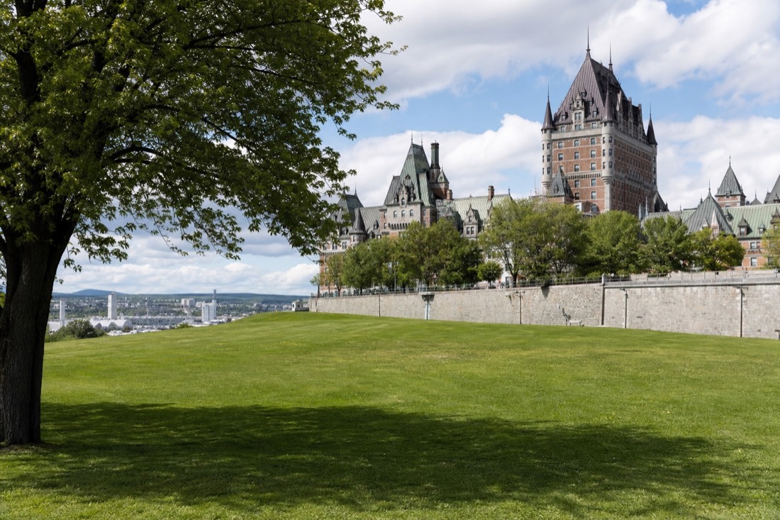 Wide green lawns of the Plains of Abraham with walkers under summer trees in Quebec City