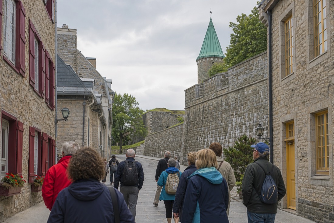 Visitors walking a narrow stone street in Old Quebec toward the city walls on a guided walking tour